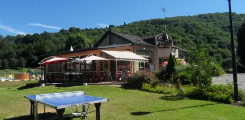 Table de ping-pong sur gazon devant le bâtiment du camping Le Moulin de Serre