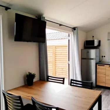 Mobil Home Fidji Premium - salle à manger avec table, chaises et télévision