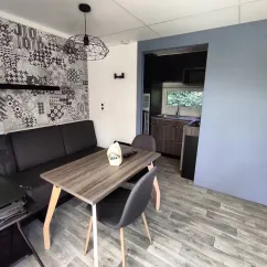Salon et salle à manger du mobil home avec table, chaises et murs décorés - Family's Camping Le Savoy