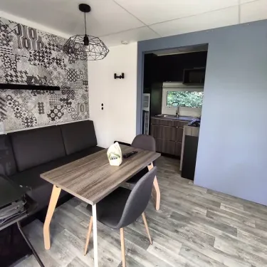Salon et salle à manger du mobil home avec table, chaises et murs décorés - Family's Camping Le Savoy