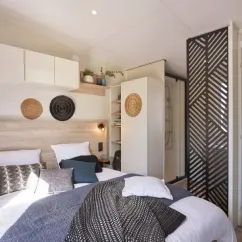 Mobil Home Tahiti Premium 3 Chambres 6 Personnes SPA - Landrezac Plage : chambre avec lit, étagères et décoration