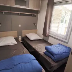 Chambre de Mobil Home Confort 3 Chambres Family's Camping Le Savoy avec deux lits et couvre-lits bleus