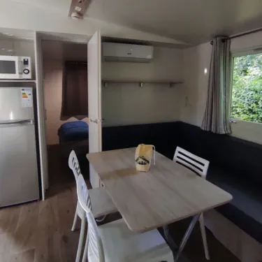 Salle à manger du Mobil Home Confort 3 Chambres Family's Camping Le Savoy avec table, chaises et réfrigérateur