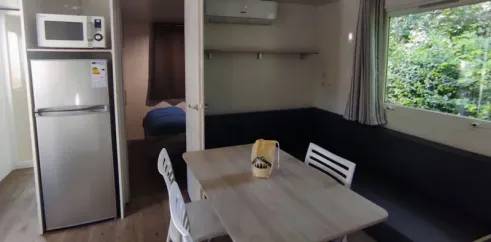 Salle à manger du Mobil Home Confort 3 Chambres Family's Camping Le Savoy avec table, chaises et réfrigérateur