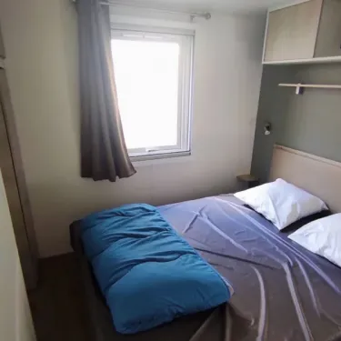 Chambre du Mobil Home Confort 3 Chambres Family's Camping Le Savoy avec lit, couvre-lits bleu et fenêtre