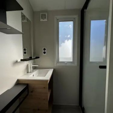 Mobil Home Confort 3 Chambres 6 Personnes - Family's Camping Le Savoy : salle de bain avec lavabo et douche