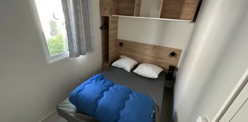 Mobil Home Confort 2 Chambres 4 Personnes - Family's Camping Le Savoy : lit, étagères, fenêtre
