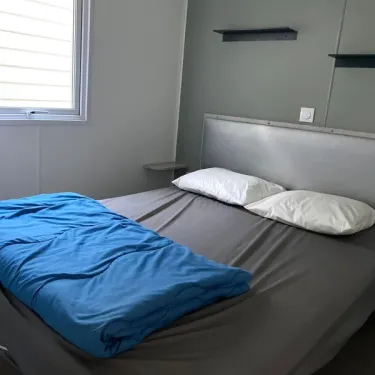 Chambre dans le Mobil Home Paradis Family des Issoux avec lit double et couvre-lit bleu