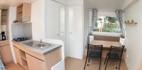 Intérieur Mobil Home Eden Thouet avec cuisine, table à manger et chaises.