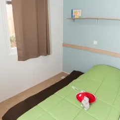 Chambre mobil home Eden Loire 3 chambres, lit vert, rideau marron, étagère murale
