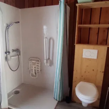 Salle de bain accessible du chalet PMR, avec douche, toilettes et rangement.