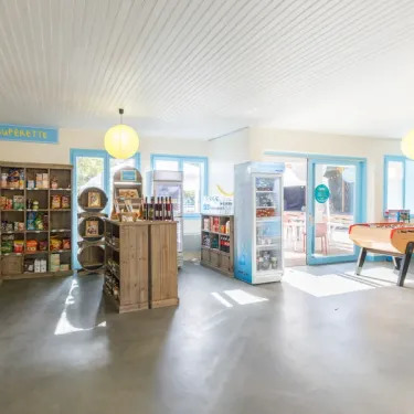 Magasin de camping avec étagères, réfrigérateur et affiche 'Supermarchés'.