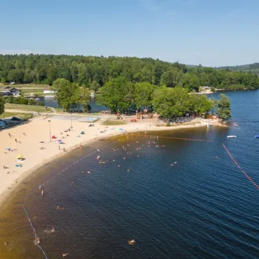 Vue aérienne du camping Paradis Les 2 Îles avec plage, eau et forêt environnante