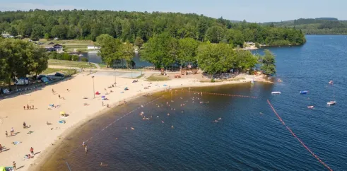 Vue aérienne du camping Paradis Les 2 Îles avec plage, eau et forêt environnante