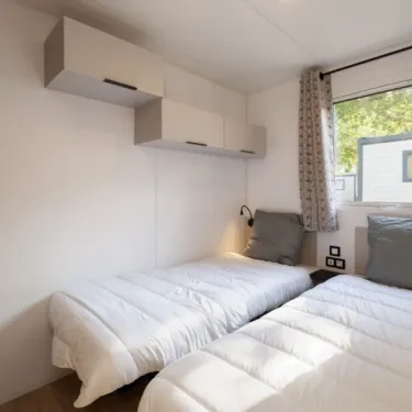 Chambre avec deux lits et rangements au Camping Paradis Les 2 Îles