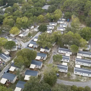 Vue aérienne du camping Paradis Albret avec des mobil-homes alignés entre les arbres.