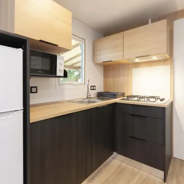 MH Confort+ 3CH – 6P - Camping Paradis Albret, cuisine équipée avec réfrigérateur et four
