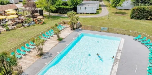 Camping La Clairière avec une piscine et des chaises longues.