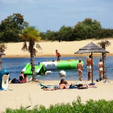 Plage avec flottement aquatique et parasols au Camping Les Viviers