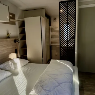 Chambre du Mobil Home Paradis Luxe Jacuzzi, lit double, armoire et séparateur décoratif