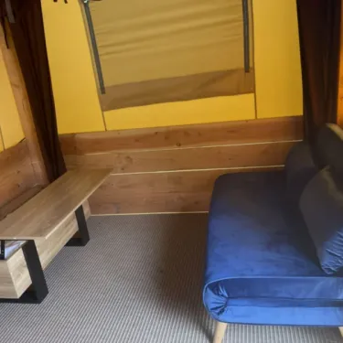 Tente Baroudeur 1 Chambre 2 Personnes Sans Sanitaires - Paradis Family des Issoux : canapé bleu, banc en bois et mur en bois