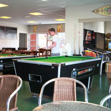 Un homme joue au billard dans la salle de jeux du Camping Les Viviers.