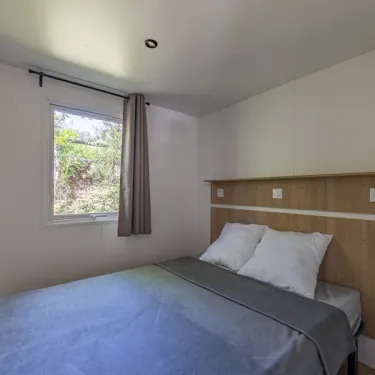 MH Confort 3CH – 6P - Camping Paradis la Baie de Ploemeur : chambre avec lit et fenêtre