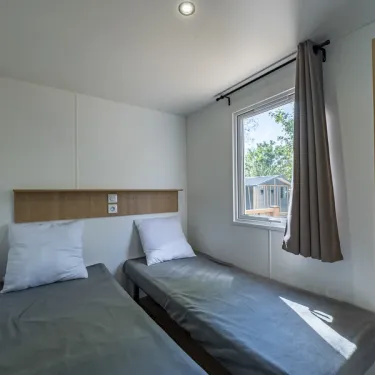 Chambre MH Confort 3CH – 6P, Camping Paradis la Baie de Ploemeur, lits simples, fenêtre, rideaux