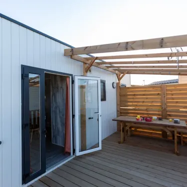 MH Premium 3CH – 6P (Sam) - Camping Paradis la Baie de Ploemeur : terrasse avec table en bois et pergola