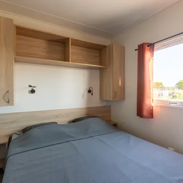 Chambre avec lit, placards et fenêtre dans le mobile home MH Premium 3CH – 6P (Sam) - Camping Paradis la Baie de Ploemeur
