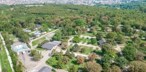 Vue aérienne du camping avec mobil-homes, arbres et piscine visible