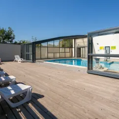 Piscine couverte avec chaises longues en bois au Camping Bel Air Village le Brabois