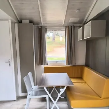 MH Classique 2CH – 4P – Camping Paradis Les Chanterelles : salle à manger avec canapé jaune et table