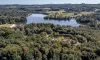 Vue aérienne d'un lac entouré de forêt dense et de zones vertes.