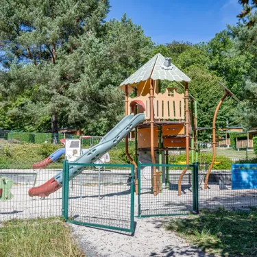 Parc infantile avec toboggan et cabane au Camping Paradis Le Coiroux.