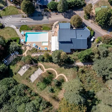 Piscine et maison au Camping Paradis Le Coiroux, entourée de verdure.