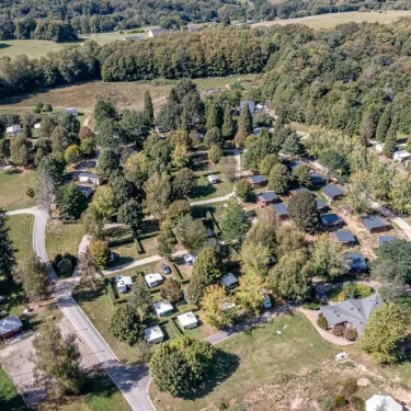 Village de camping avec mobile homes et forêt environnante.