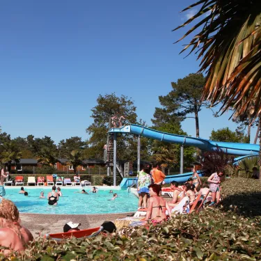 Piscine avec toboggan bleu et visiteurs autour, au Camping Les Viviers.