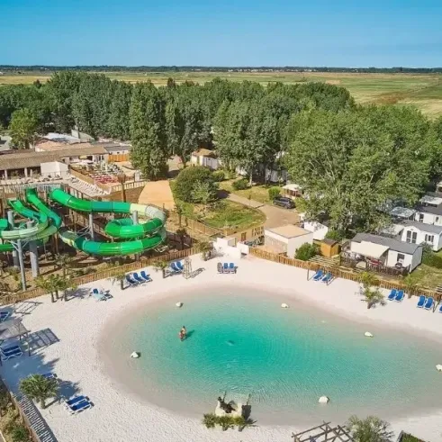 Piscine avec toboggan vert et chaises longues au Camping Aunis Club Vendée