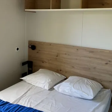 Lit double avec tête de lit en bois et oreiller blanc