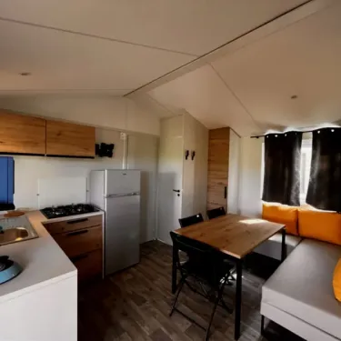 Cuisine et salle à manger dans mobil home avec table et canapé