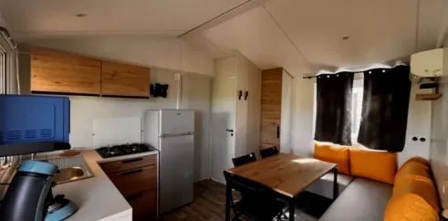 Cuisine et salle à manger dans mobil home avec table et canapé
