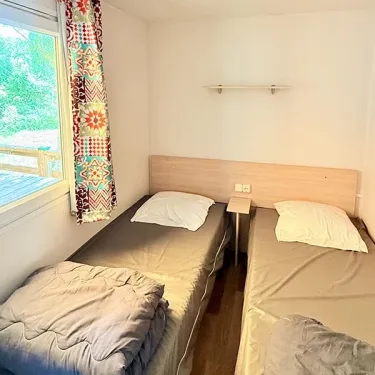 Chambre Mobil Home Paradis Family les Rives de l'Hérault avec deux lits et fenêtre