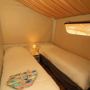 Lodge Maasaï 2CH – 4P - Camping Paradis Le Coiroux : deux lits, lampe de chevet