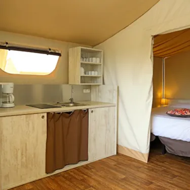 Lodge Maasaï 2CH – 4P - Camping Paradis Le Coiroux : cuisine et lit dans une tente