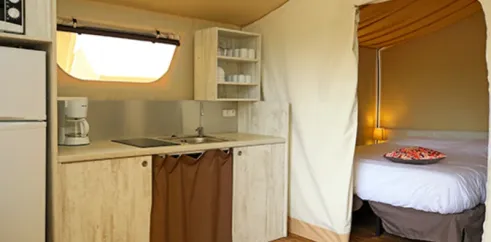 Lodge Maasaï 2CH – 4P - Camping Paradis Le Coiroux : cuisine et lit dans une tente