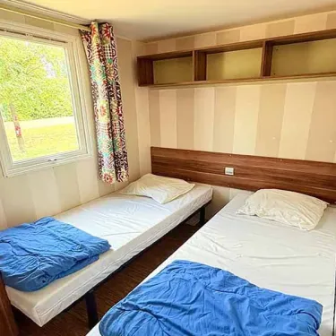 Mobil Home Family 4 Chambres 8 Personnes Clim TV - Paradis Family les Rives de l'Hérault : chambre avec 2 lits simples et rideaux colorés