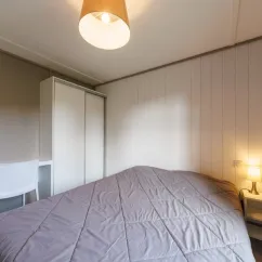 Chambre avec lit double et armoire dans le cottage Premium PMR 2CH – 4P – Camping Bel Air Village Les Demeures du Lac