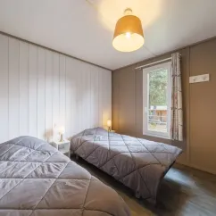 Chambre avec deux lits simples et fenêtre dans le cottage Premium PMR 2CH – 4P – Camping Bel Air Village Les Demeures du Lac