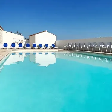 Piscine avec chaises longues bleues au Camping Le Pavillon Bleu
